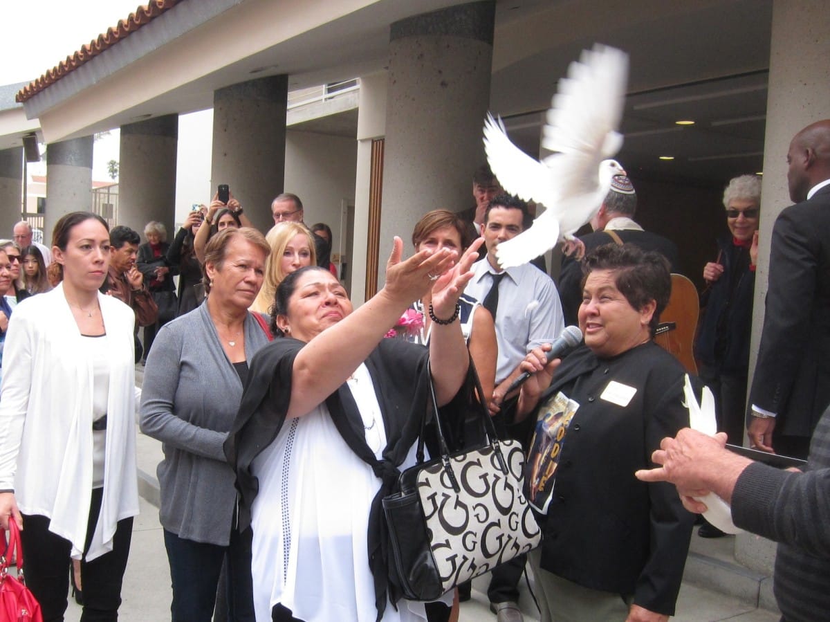 Ramona Franco, who lost her husband and daughter in last year’s mass shooting in Santa Monica, releases a dove to remember her family members at the interfaith service held to commemorate the one-year anniversary of the shooting. (Photos by Saul Rubin)