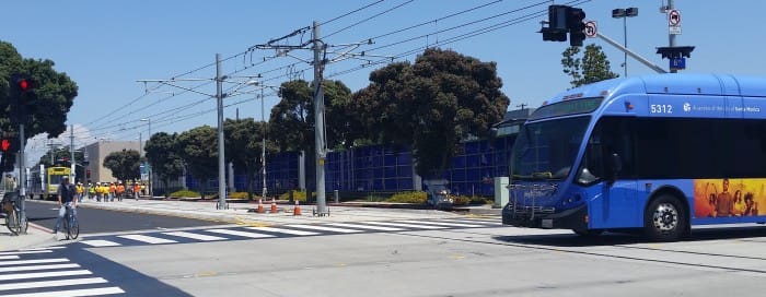 A Rapid 7 crosses the Expo tracks by the Big Blue Bus facility at Colorado and 6th Street as a test train approaches. (Photo by Jason Islas/Santa Monica Next)