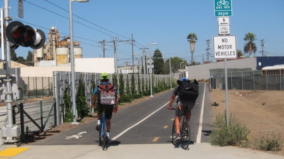 Two cyclists turn onto the beginning of the dedicated bike path heading east from the 17th Street/SMC metro stop.